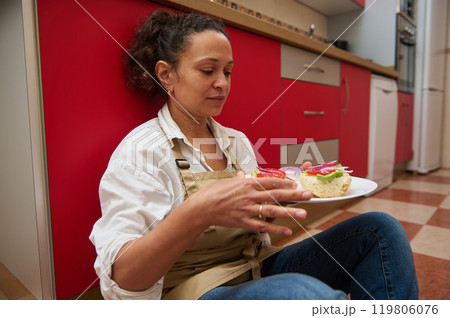 Woman sitting in kitchen enjoying a fresh homemade sandwich 119806076