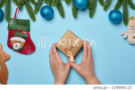 Female hands holding gift box on blue background, top view 119806113