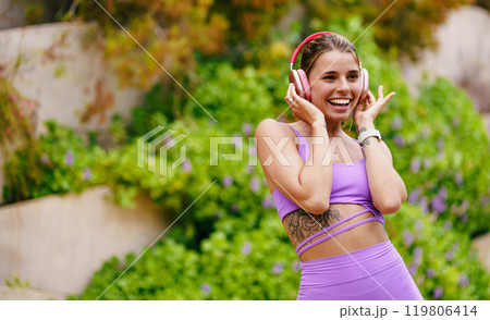 A Joyful Woman Wearing Workout Gear, Enjoying the Uplifting Music While Outdoors 119806414