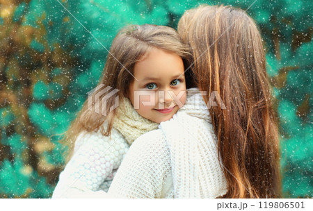 Happy little girl child hugging her mother in winter day over tree 119806501