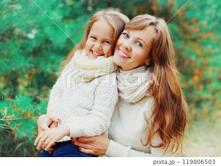Happy smiling little girl child and mother in winter day over tree 119806503