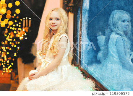Portrait smiling little girl child with snowball toy over christmas tree at home near frozen mirror 119806575
