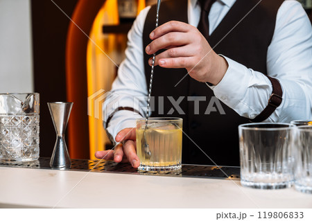 Bartender preparing a cocktail at a stylish bar during an evening event 119806833
