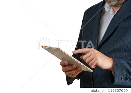 Professional businessman in a formal suit using a tablet device against a solid color backdrop 119807099