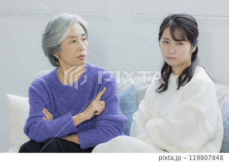 リビングで喧嘩をするシニア女性と若い女性 リビングで喧嘩をするシニア女性と若い女性 119807848