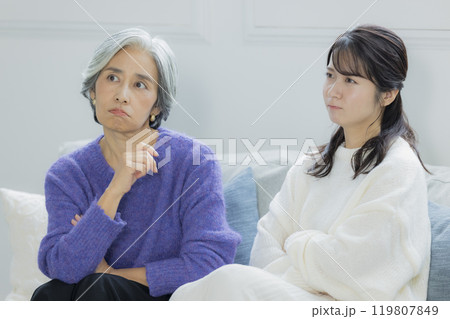リビングで喧嘩をするシニア女性と若い女性 リビングで喧嘩をするシニア女性と若い女性 119807849
