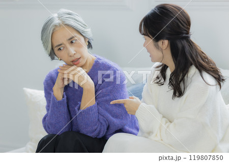 リビングで喧嘩をするシニア女性と若い女性 リビングで喧嘩をするシニア女性と若い女性 119807850