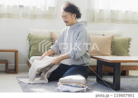 洗濯物を畳む男性 119807901