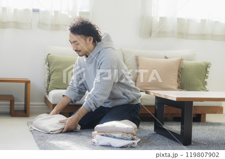洗濯物を畳む男性 119807902