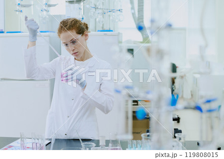 Scientist engaged in laboratory work with scientific equipment, performing chemical experiments with precision in controlled environment, wearing protective gear Scientist engaged in laboratory work with scientific equipment, performing chemical experiments with precision in controlled environment, wearing protective gear 119808015