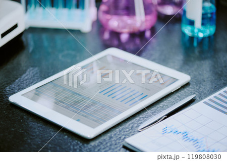Close-up of white tablet displaying scientific graphs on lab table, surrounded by lab equipment and documents, indicating research and analysis scene Close-up of white tablet displaying scientific graphs on lab table, surrounded by lab equipment and documents, indicating research and analysis scene 119808030