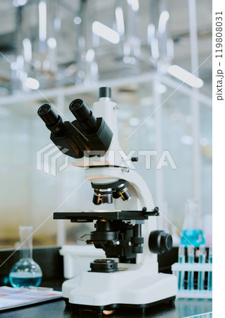 Close-up of advanced microscope in a high-tech laboratory environment featuring equipment and glass containers in the background Close-up of advanced microscope in a high-tech laboratory environment featuring equipment and glass containers in the background 119808031