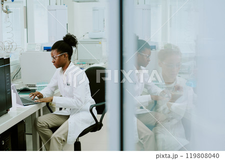 Scientist sitting in laboratory setting, engaged in research and using advanced equipment. Displaying focus and dedication, surrounded by high-tech machinery and laboratory tools 119808040