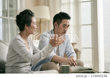 young asian adult son and elderly mother conversing at home 119809186