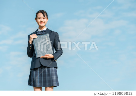青空の下で卒業証書を持つ卒業生の女子中学生 119809812