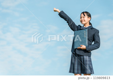 青空の下で卒業証書を持ってガッツポーズする卒業生の女子中学生 119809813