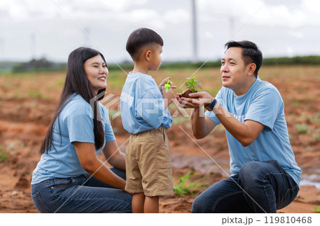 family of three, a man and two children, are standing in a field 119810468