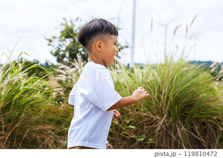 young boy is running through a field of tall grass young boy is running through a field of tall grass 119810472