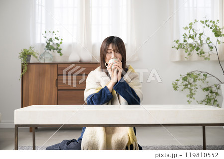 冬のリビングで飲み物を飲むくつろぐ若い女性 119810552
