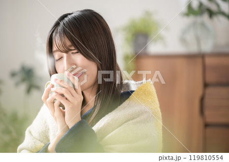 冬のリビングで温かい飲み物を飲むくつろぐ目を閉じる若い女性のクローズアップ 119810554