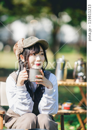 キャンプで落ち着きながら飲み物を飲む女性 キャンプで落ち着きながら飲み物を飲む女性 119811213