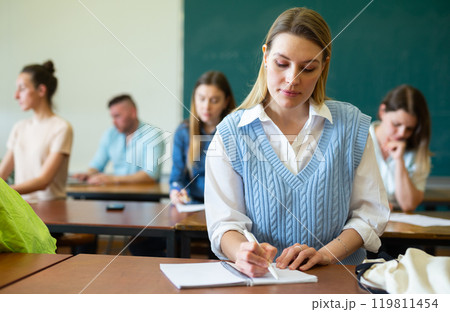 Woman university student writing in classroom Woman university student writing in classroom 119811454