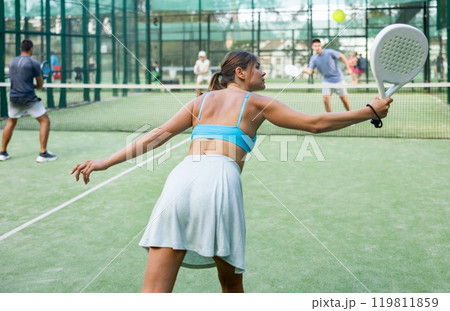 Rear view of young woman playing padel on open court 119811859