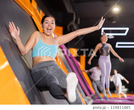 Young woman in sport clothes jumping on vertical trampoline Young woman in sport clothes jumping on vertical trampoline 119811865