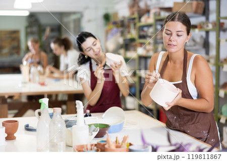 Girl performs polishing of ceramic product Girl performs polishing of ceramic product 119811867