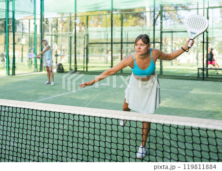 Young female paddle tennis player performing left hand forehand Young female paddle tennis player performing left hand forehand 119811884