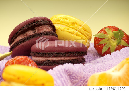 Assortment of macaroons and fruits on purple cloth 119811902