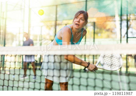 Young woman hitting ball with backhand during paddleball match outdoor 119811987