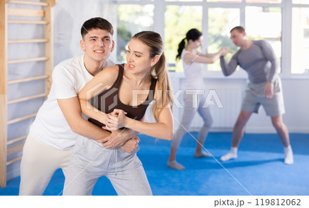 Young girl practicing self-defense techniques in pairs with guy 119812062