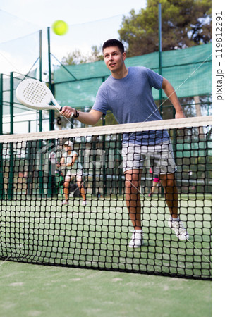 Young guy playing padel tennis on open court in summer 119812291