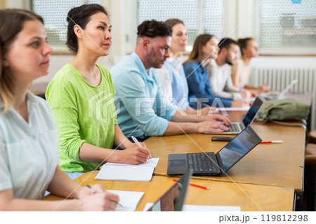 Group of students searches for information on a laptop and writes it out 119812298