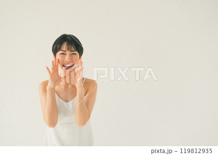 口に手を当てて何かを叫ぶキャミソール姿の若い女性 口に手を当てて何かを叫ぶキャミソール姿の若い女性 119812935