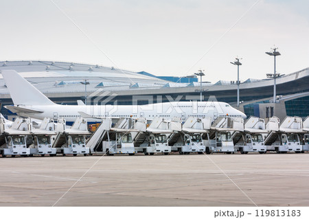 Passenger airplane near the airport terminal behind the rows of boarding ramps 119813183