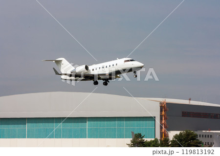Business jet taking off on the background of a hangar 119813192