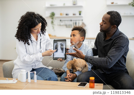 Female doctor discussing lung x-ray with concerned family at home Female doctor discussing lung x-ray with concerned family at home 119813346