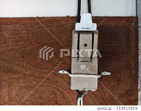 An old, dusty electrical cutout filled with dirt inside the house. 119815829