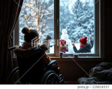 Teenage girl wheelchair user watches children playing in winter on  playground from window of dark room. 119816557