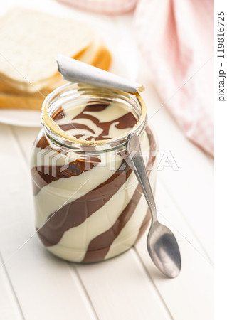 Chocolate cream spread in jar on white table. Chocolate cream spread in jar on white table. 119816725