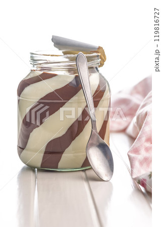 Chocolate cream spread in jar on white table. Chocolate cream spread in jar on white table. 119816727