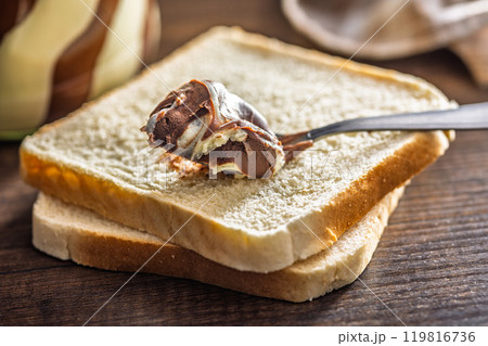 Chocolate cream spread in spoon on bread. 119816736