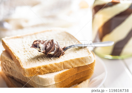 Chocolate cream spread in spoon on bread. 119816738