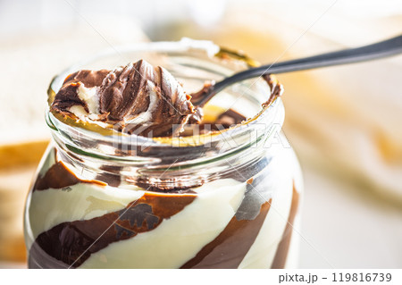 Chocolate cream spread on spoon in jar. Chocolate cream spread on spoon in jar. 119816739