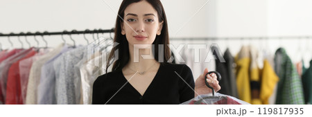 Employee holds blouse covered with foil at dry cleaning 119817935