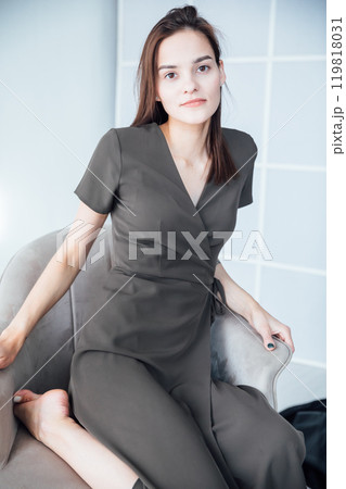 Portrait of a beautiful slender woman in a gray summer dress on an armchair 119818031