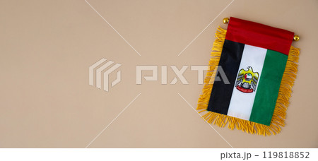 National symbol of UAE. United Arab Emirates small flag with Peregrine falcon on neutral beige background. Copy space for your text. Concept of Independence  119818852