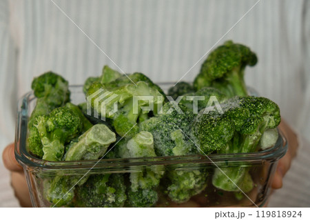 Unrecognizable woman showing into camera frozen food broccoli florets homemade. Harvesting concept. Stocking up vegetables for winter storage Unrecognizable woman showing into camera frozen food broccoli florets homemade. Harvesting concept. Stocking up vegetables for winter storage 119818924